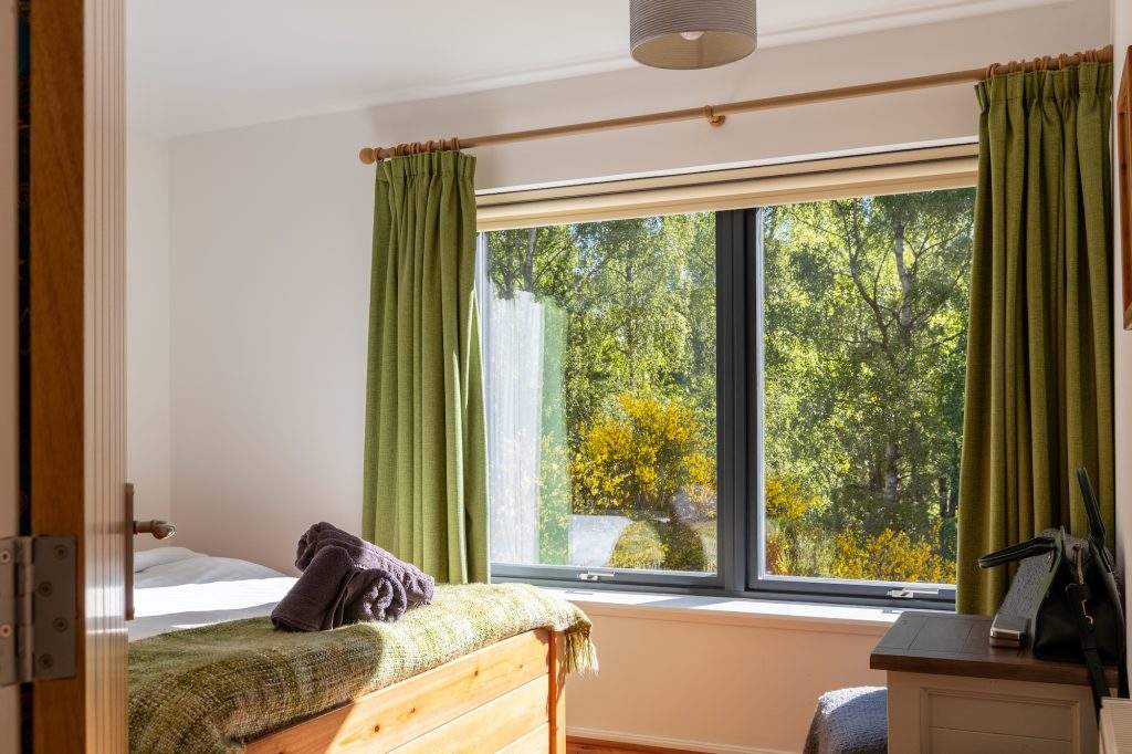 Bright queen bedroom with green curtains, wooden beds and garden view